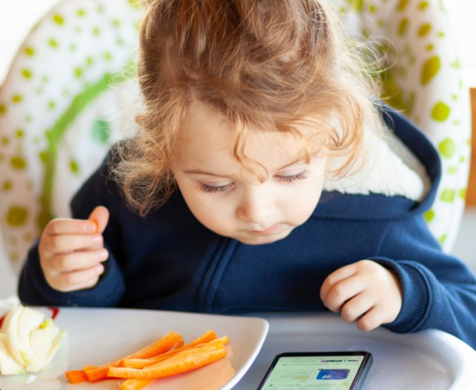 Toddler Eats While Watching Movies On The Mobile Phone.